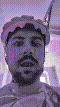 a selfie of a white person, wearing either headphones or a helmet, making an odd expression. the photo is edited to be colorized into a monochrome purple-ish color palette.